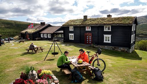 Cyclists planning their trip at a table outside Grimsdalshytta Lodge in Norway