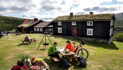 Cyclists planning their trip at a table outside Grimsdalshytta Lodge in Norway