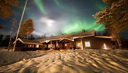 Nellim Wilderness Hotel main building with northern lights above it