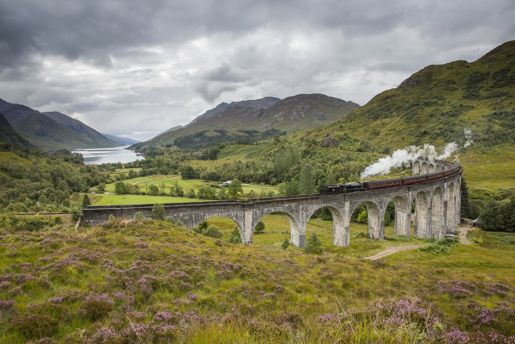 View down the valley of a train going over the Glenfinnan Viaduct in The Highlands in Scotland