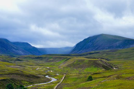 A river weaving through the Cairngorms National Park with the mountains beyond in Scotland