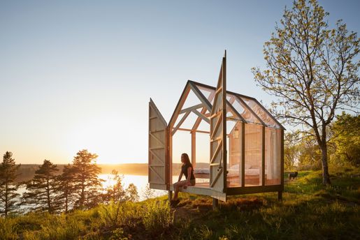 A glass cabin perched on the water's edge in Southwest Sweden during summer