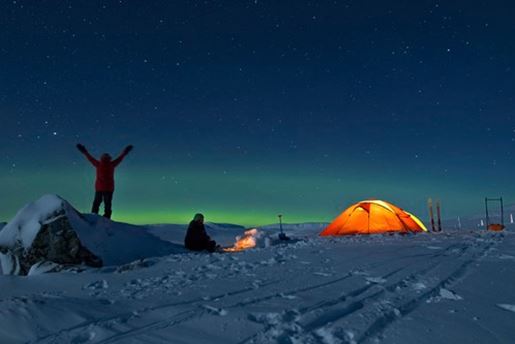 A tent and small camp under the starry sky on a polar night in Svalbard in winter.