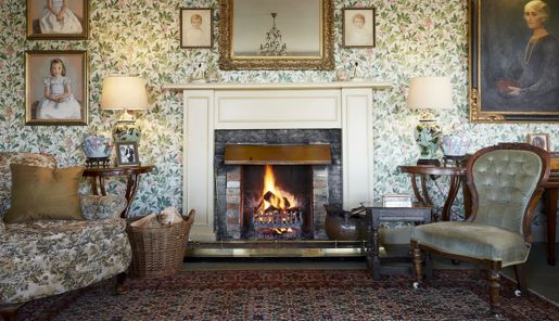 The ornate fireplace and wallpaper in the drawing room of the Kinloch Lodge in the Scottish Highlands